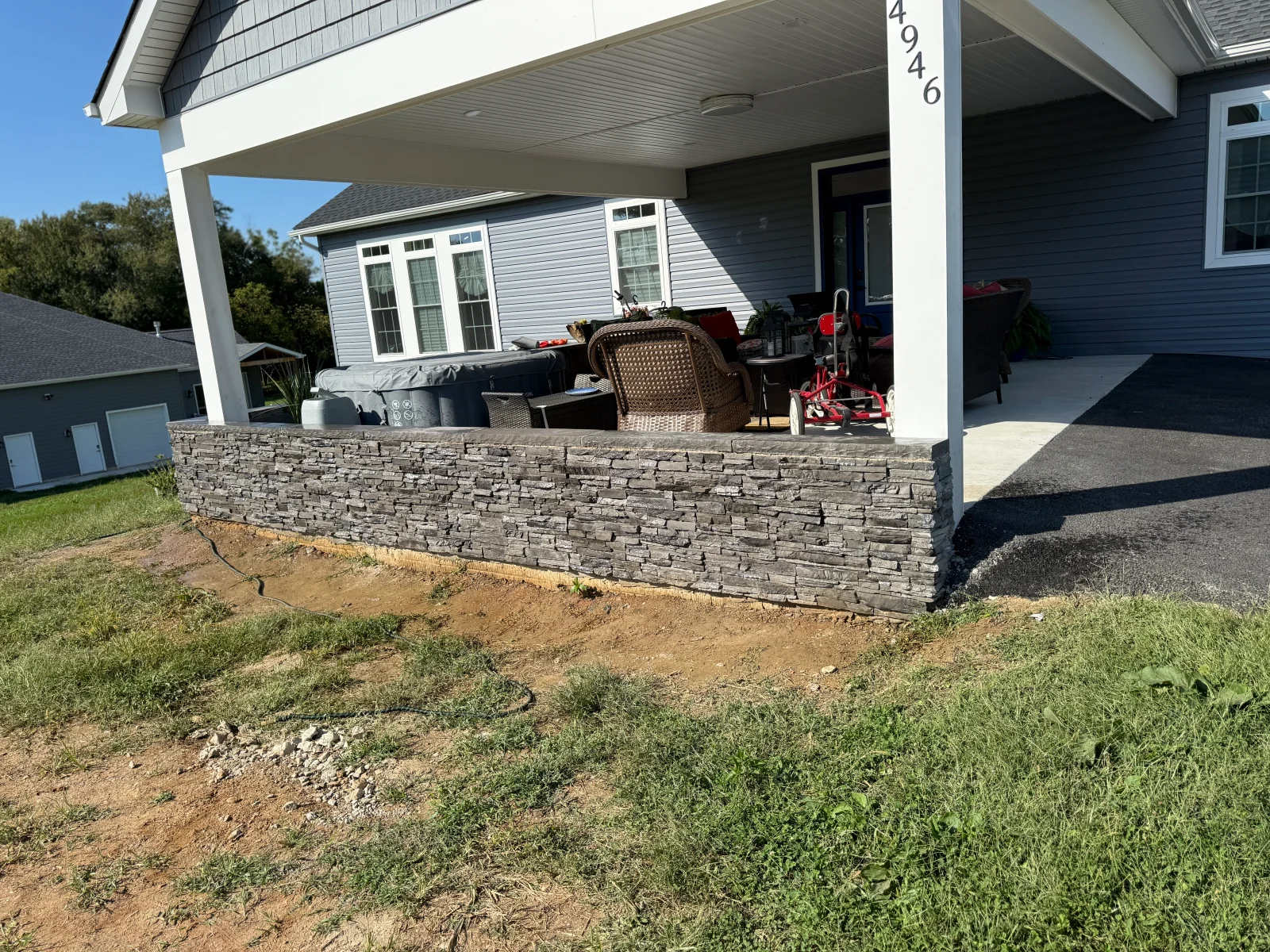 Gray stacked stone retaining wall with running bond pattern along porch foundation