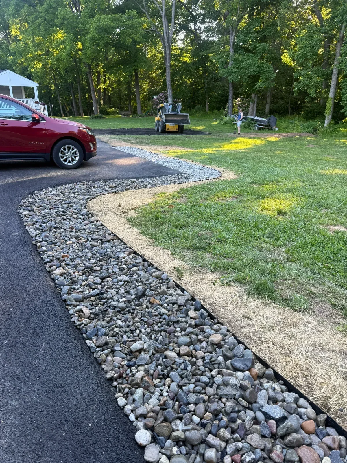 Gravel driveway with metal edging and crushed stone base material alongside asphalt