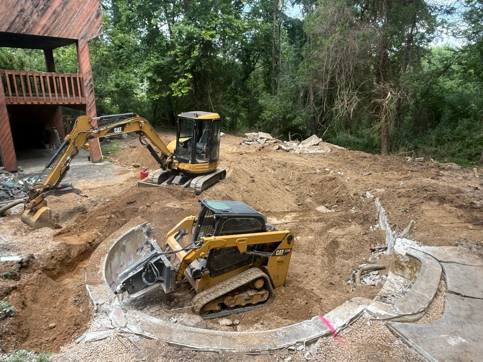 CAT excavators and compact loaders clearing and grading residential property with debris removal