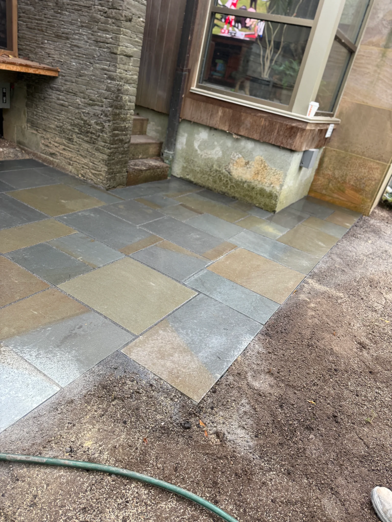Multi-colored slate and sandstone patio pavers laid in geometric pattern with clean grout joints