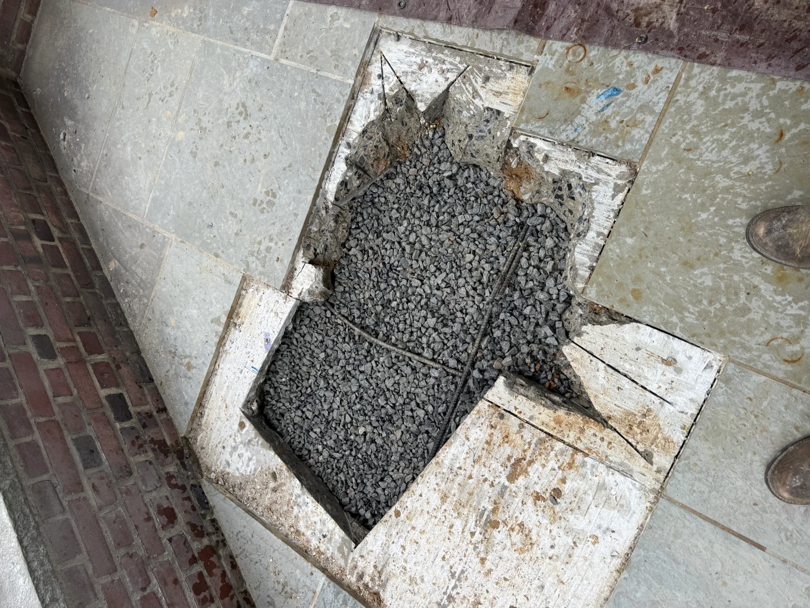 Crushed stone drainage base installed in concrete-framed opening with hardscape edging