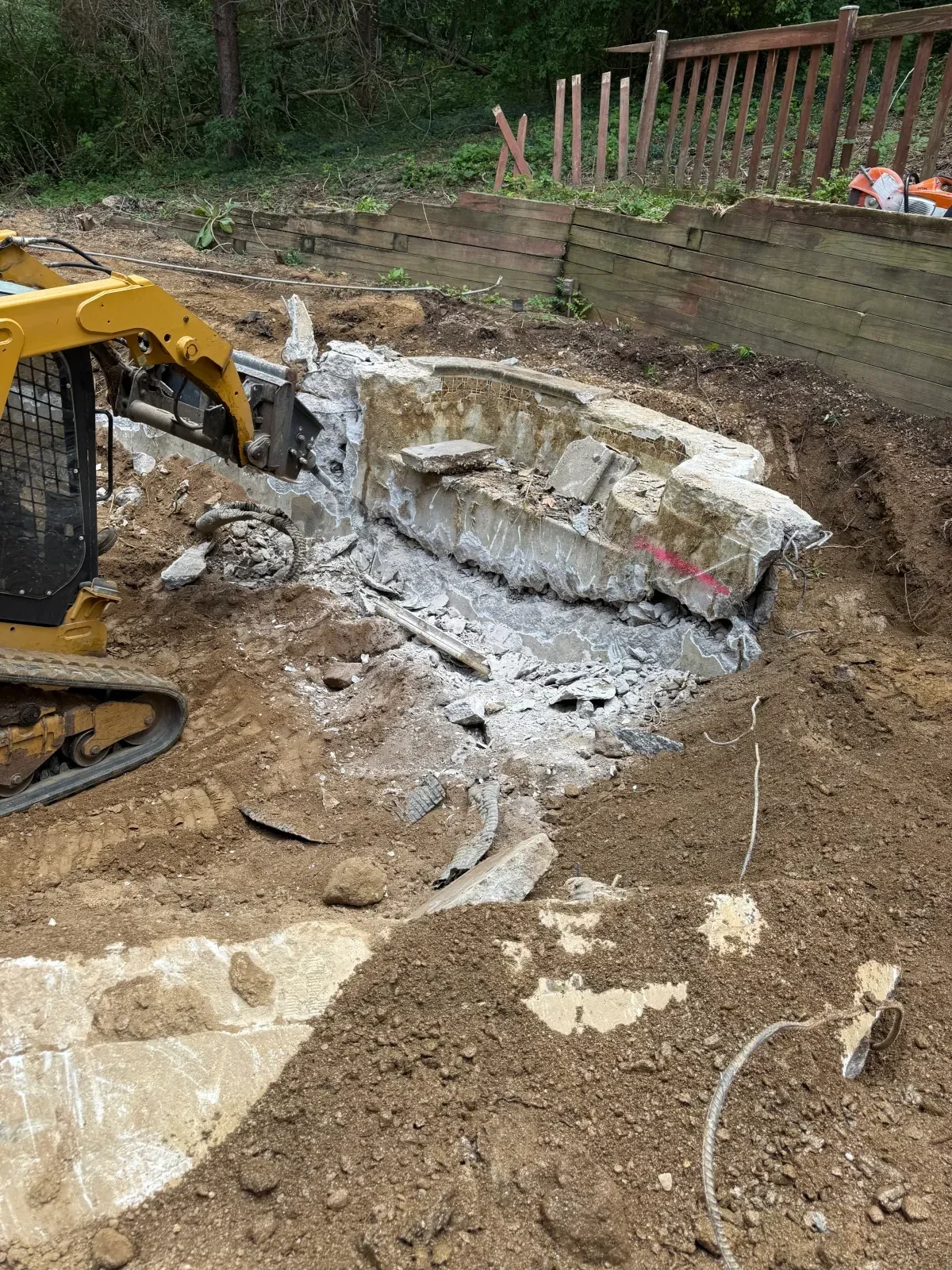 Excavator removing broken concrete and debris from cleared residential lot