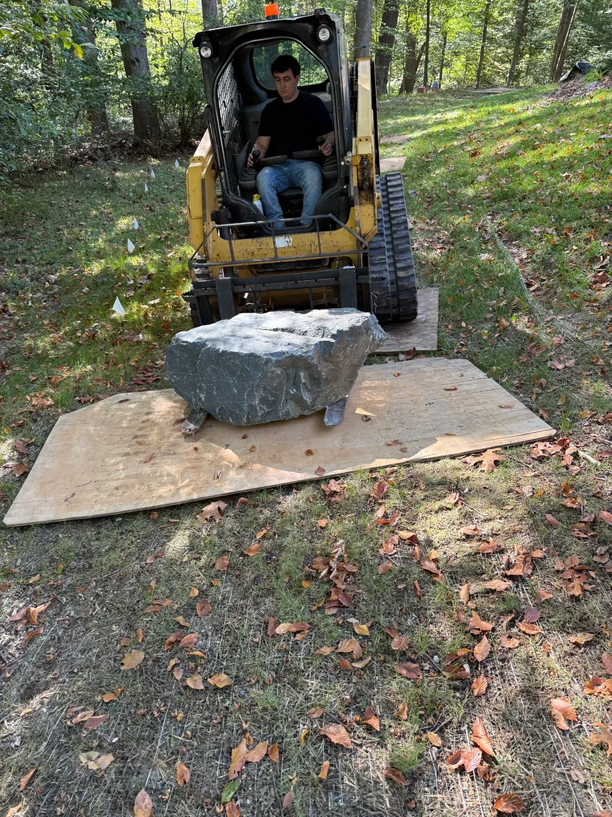 Dark slate stone being positioned with equipment during hardscape installation