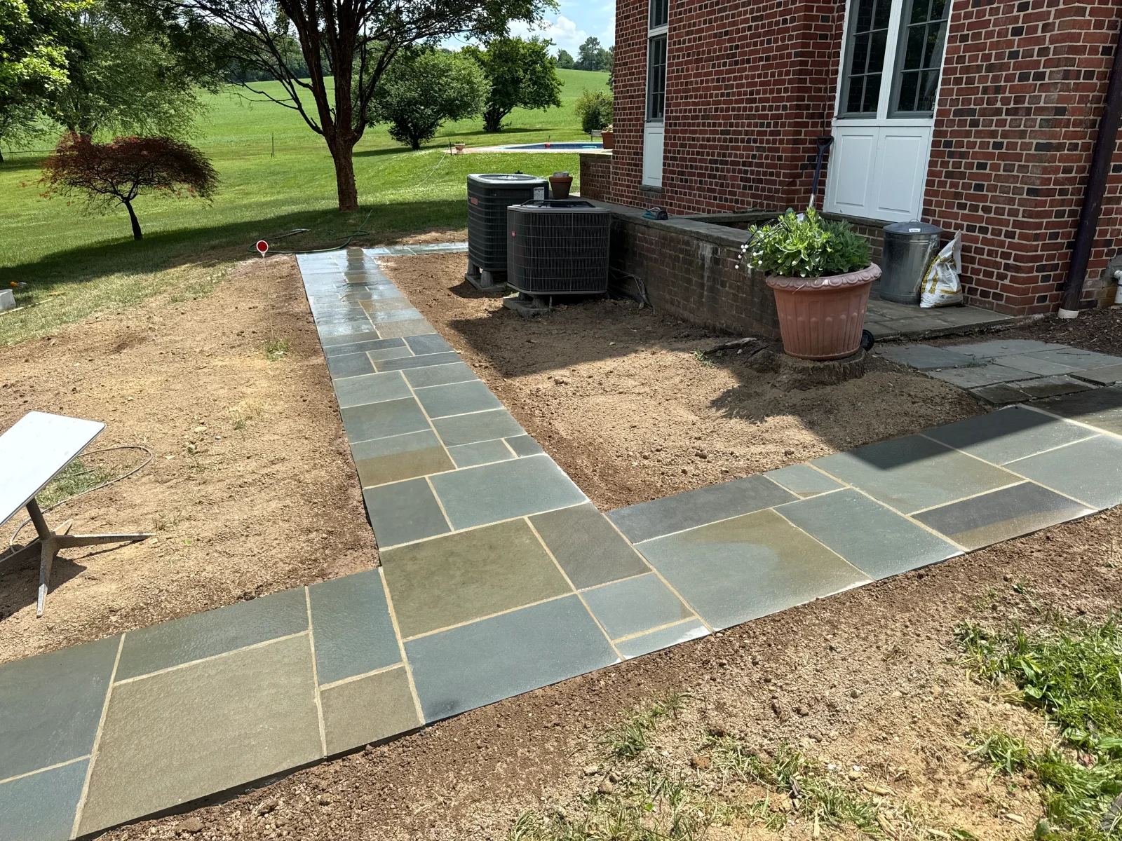 Slate stone walkway with tan mortar joints installed next to brick home and HVAC units